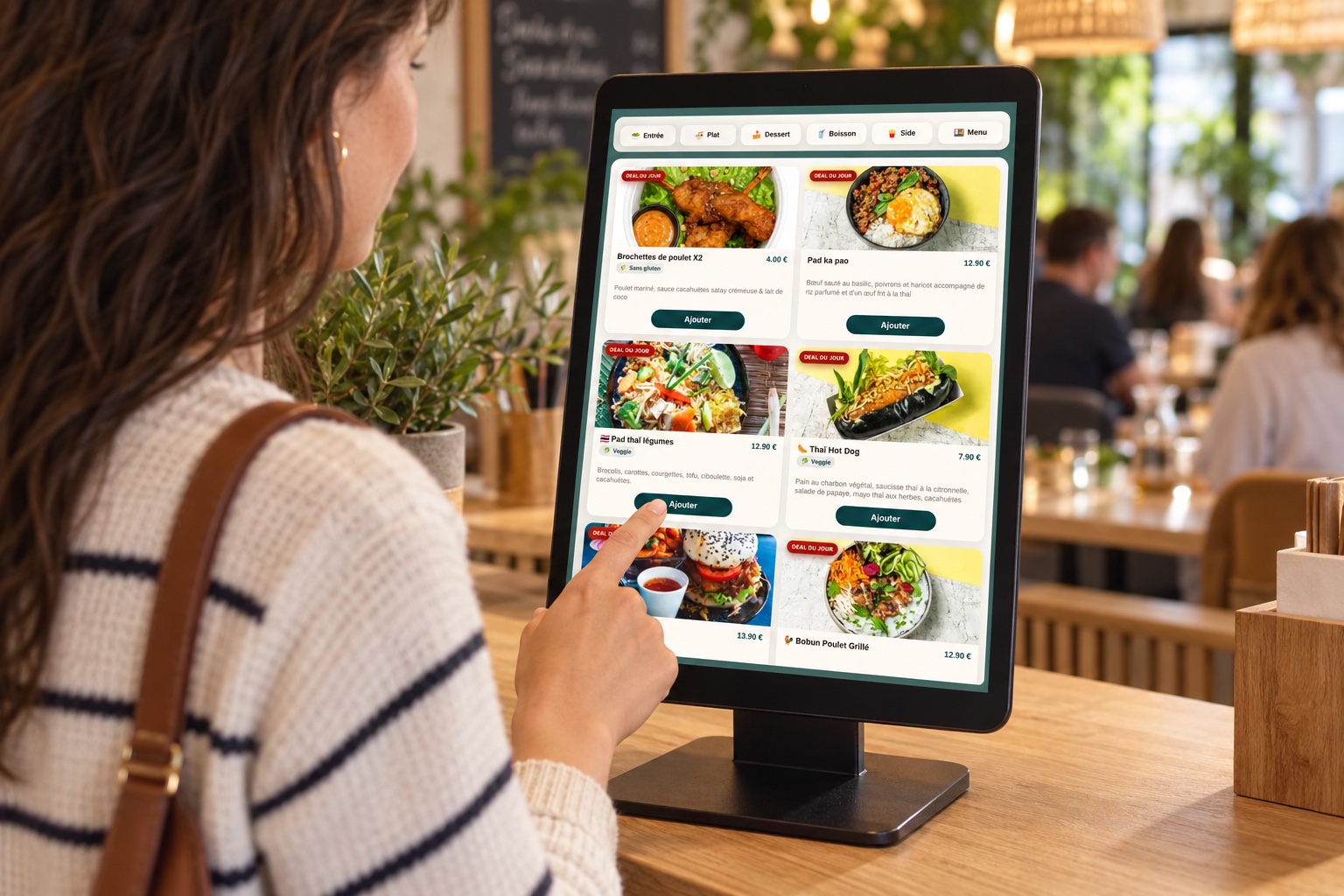Une cliente utilise une borne tactile de commande dans un restaurant